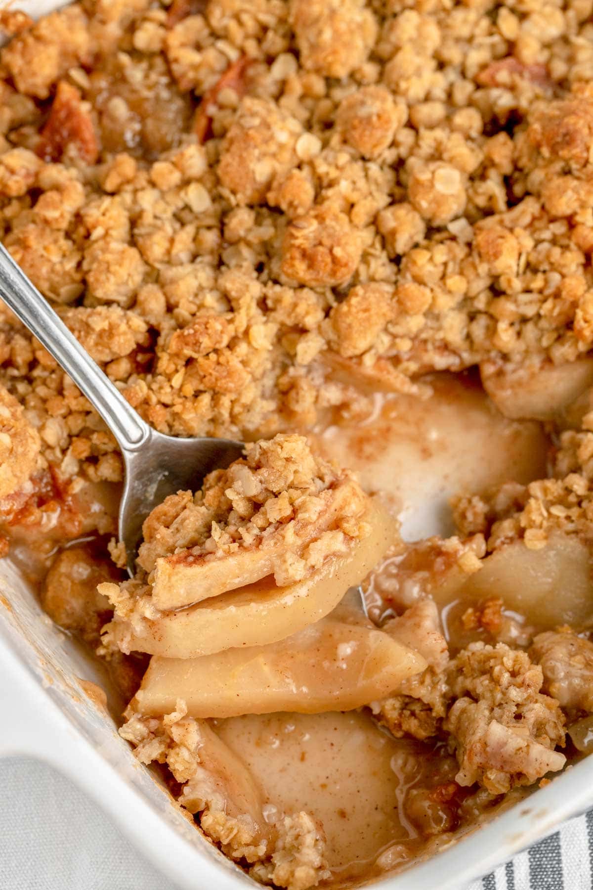 Close up of scooping recipe for apple crisp from a baking dish.