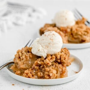 Easy apple crisp recipe on white plate with vanilla ice cream on top.