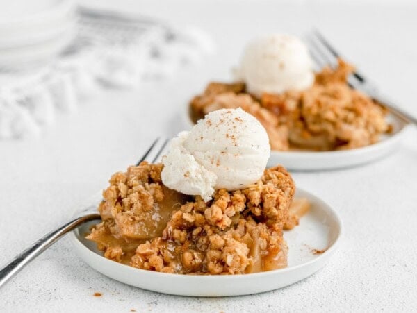 Easy apple crisp recipe on white plate with vanilla ice cream on top.