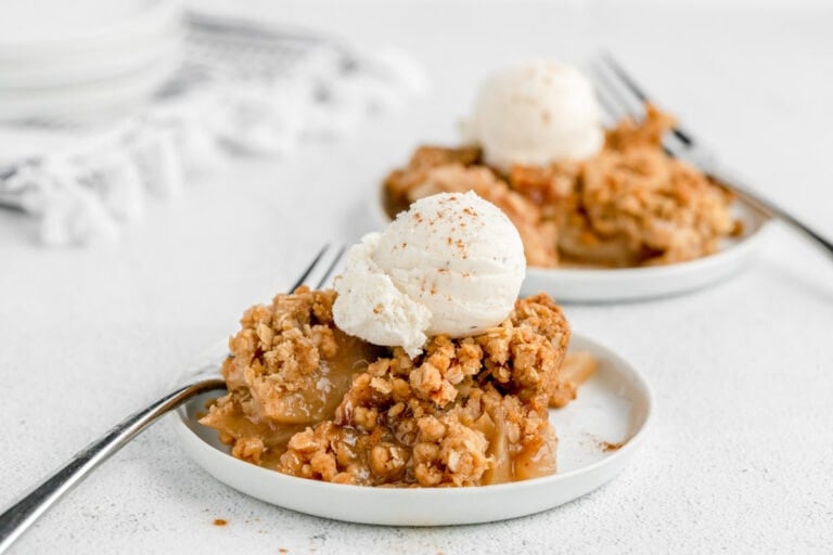 Easy apple crisp recipe on white plate with vanilla ice cream on top.
