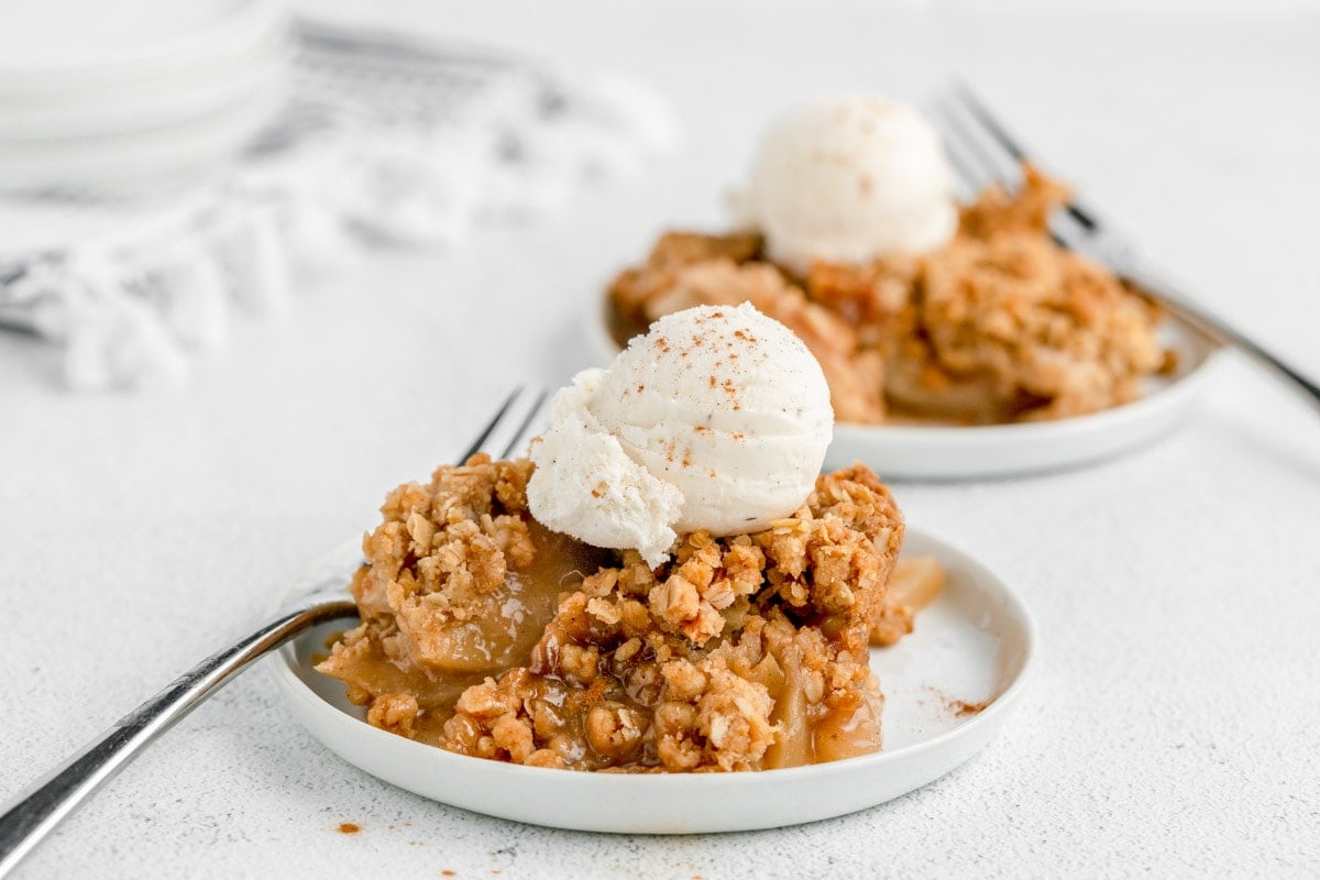 Apple Crisp Recipe topped with vanilla ice cream and caramel syrup.