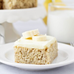 A slice of frosted banana bars on a white plate.
