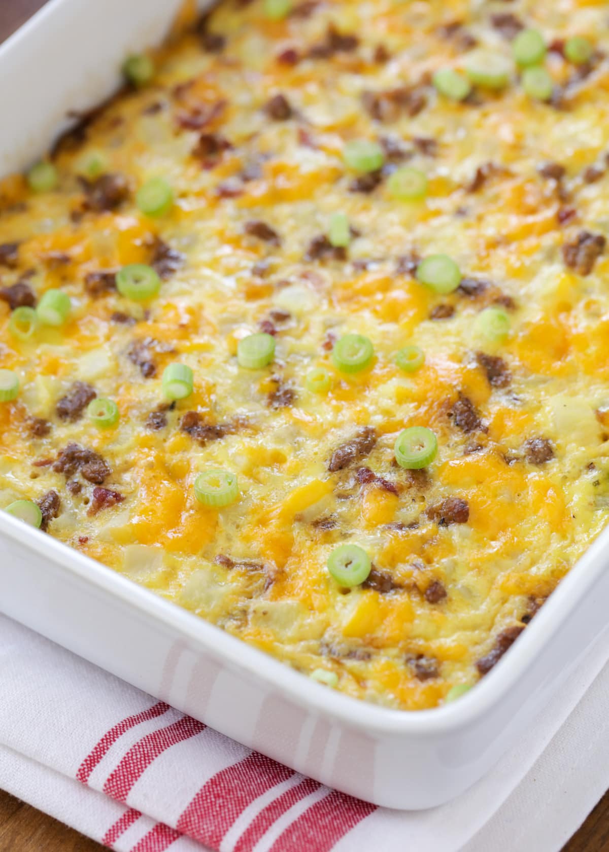 Close up of cheesy breakfast potato casserole topped with green onions.