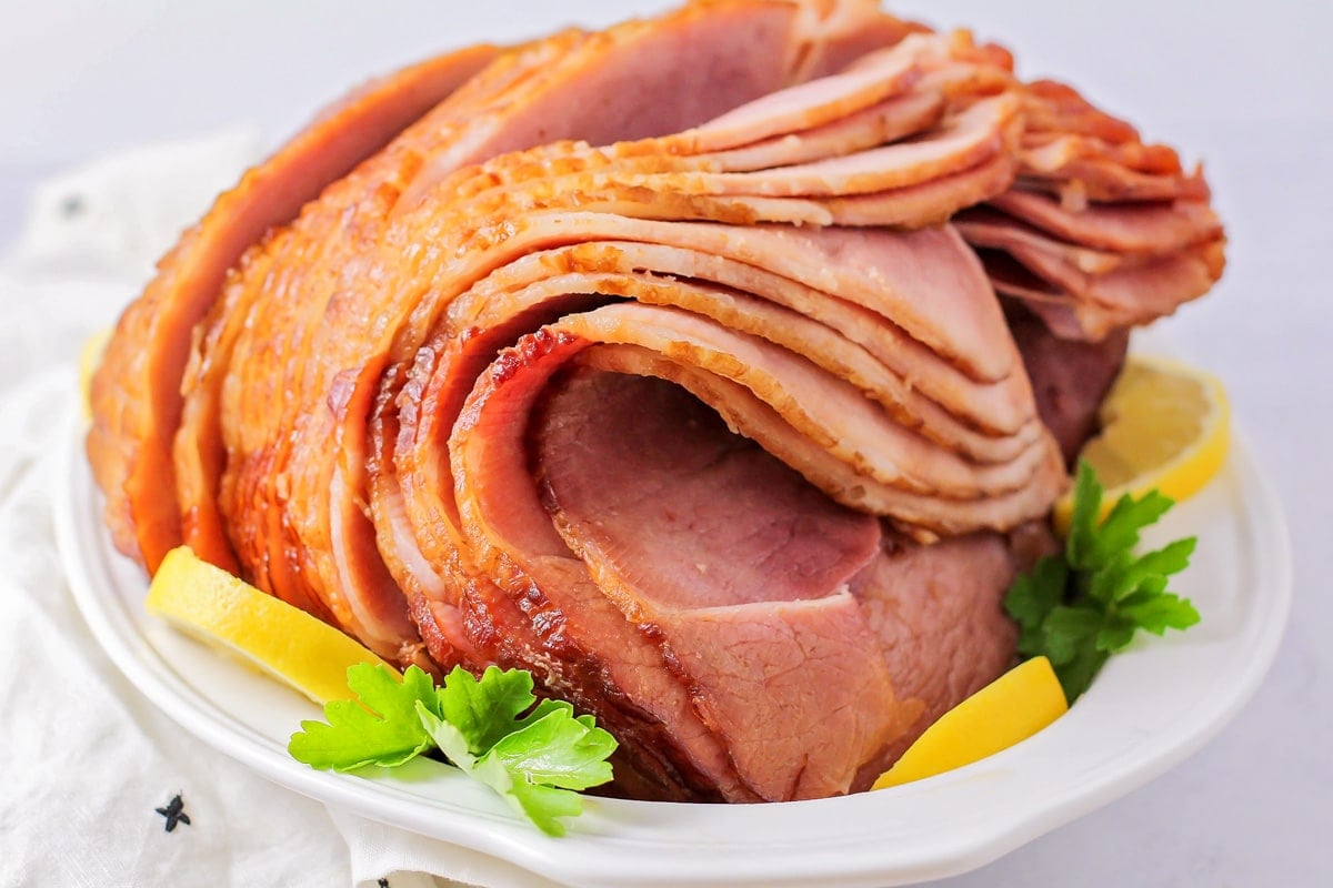 A ham served on a white platter.
