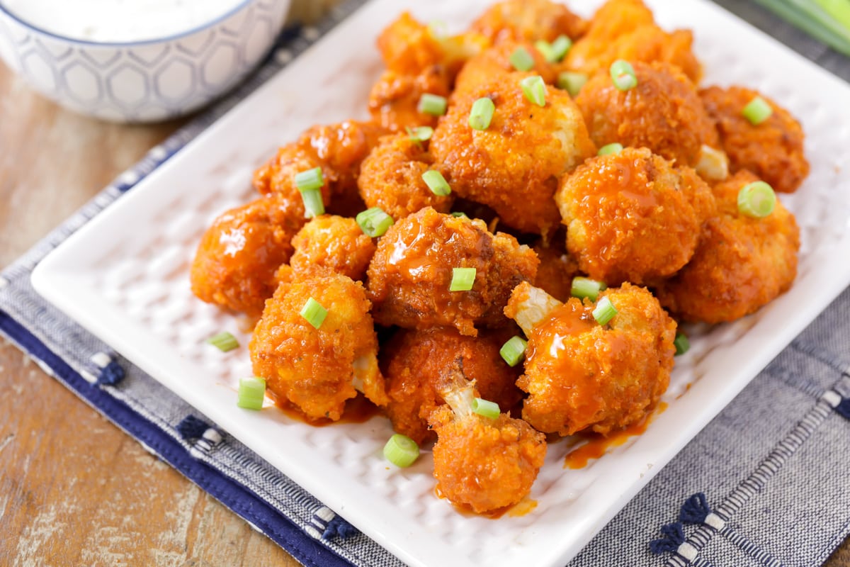 Close up of buffalo cauliflower topped with sauce and green onions.