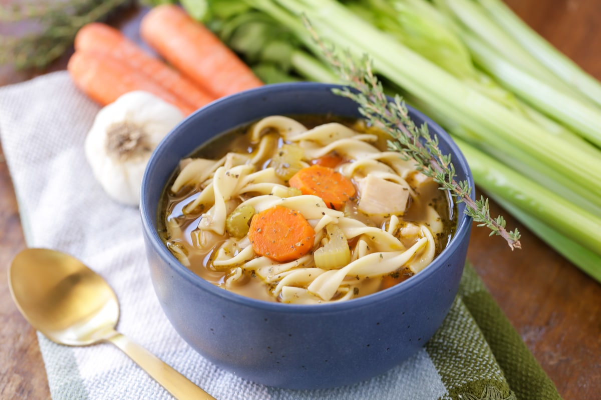 A blue bowl filled with chicken noodle soup.