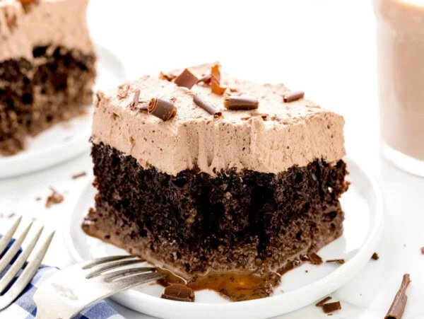 A slice of chocolate tres leches cake with a bite missing.