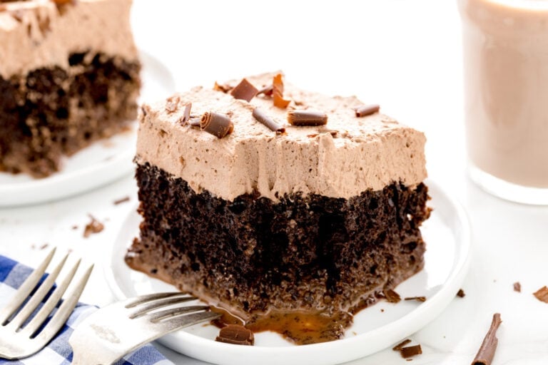 A slice of chocolate tres leches cake with a bite missing.