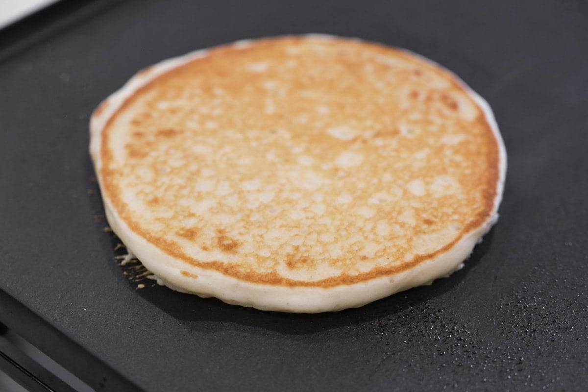 Pancake on a griddle turned over and browned.