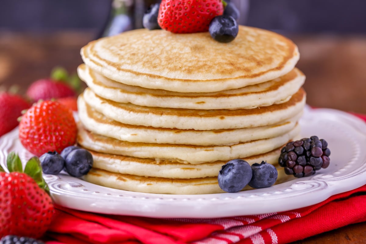 A stack of pancakes topped with fresh berries on a white plate. 