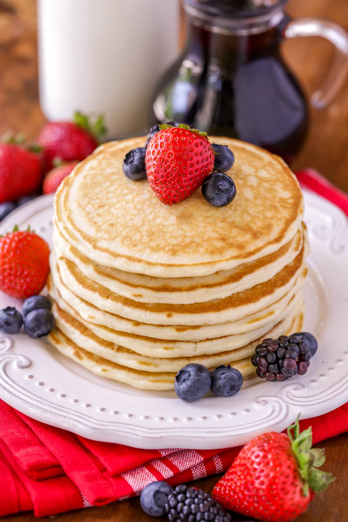Easy pancake recipe stacked on plate with fruit on top.