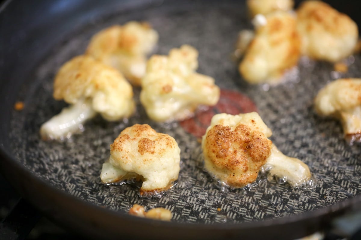 Lightly brown fried cauliflower in a pan of oil.
