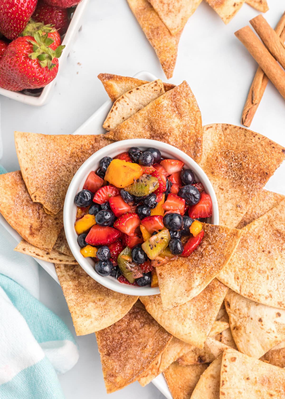 A bowl of fresh fruit served with cinnamon chips.