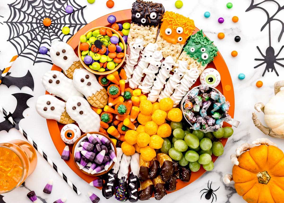 Halloween candy charcuterie board filled with nutter butter ghosts, candy, and fruit.
