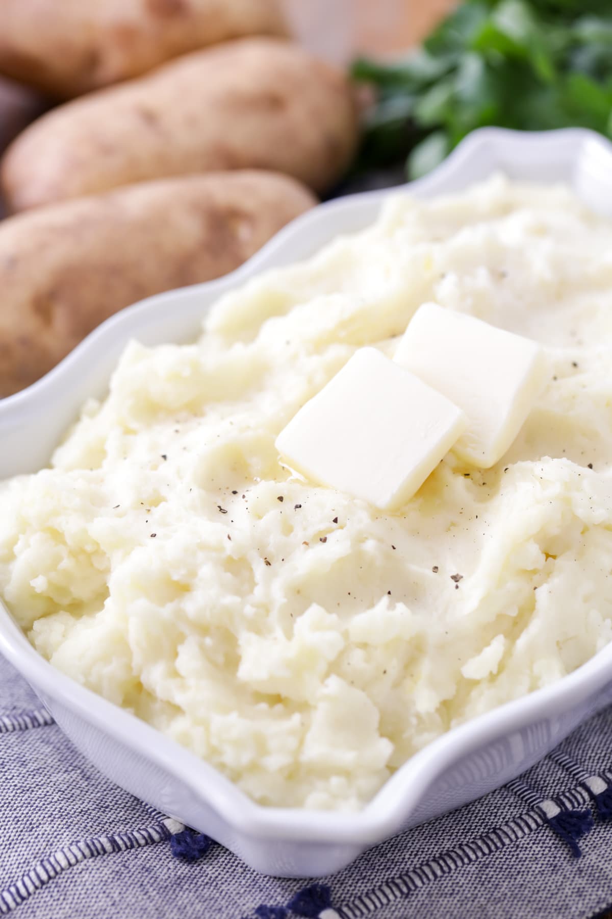 Best Mashed Potatoes Recipe topped with butter in a white dish.