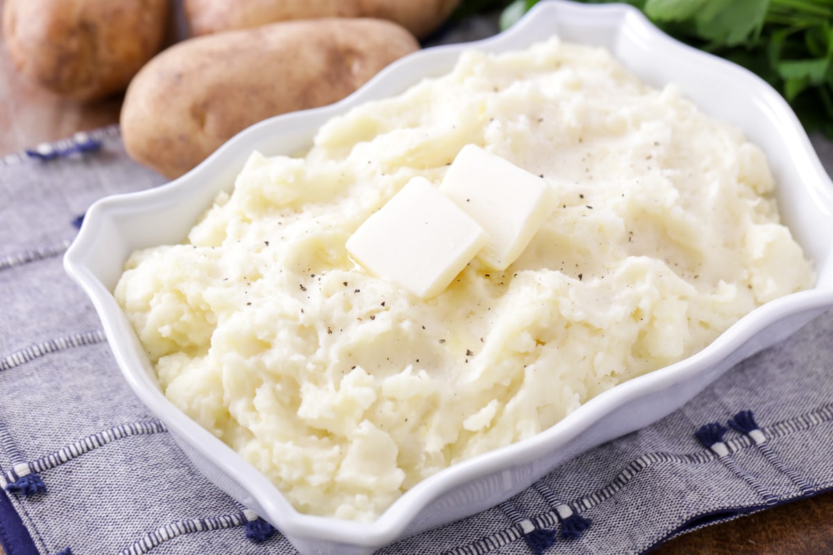 Homemade mashed potatoes in white serving dish.