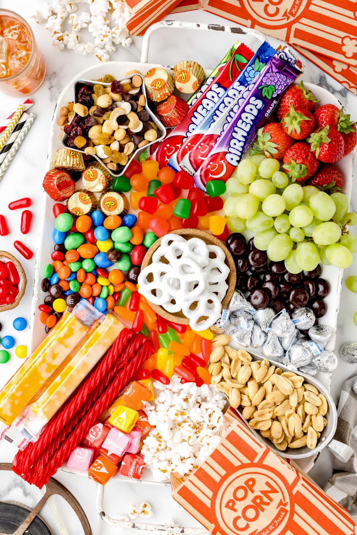 Close up of a completely movie night charcuterie board filled with candy, fruit, and nuts.