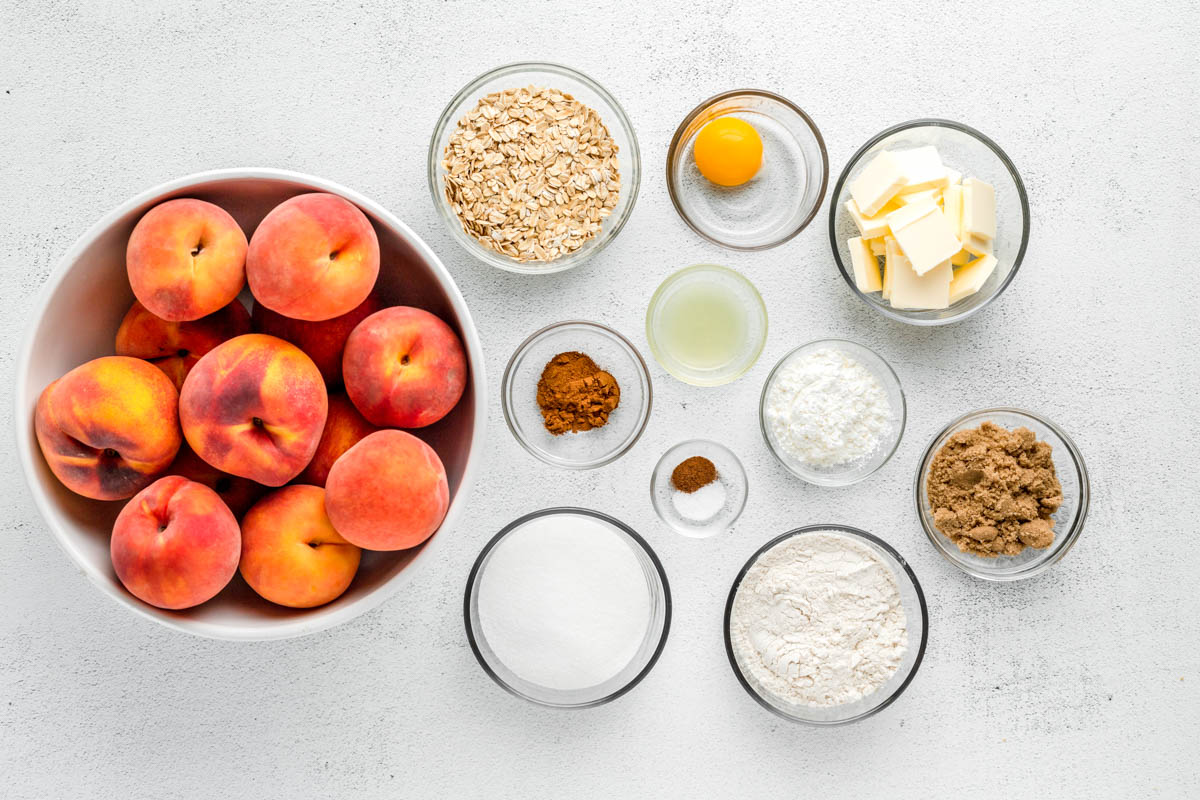 Crisp topping ingredients and fresh peaches set out on a kitchen counter.