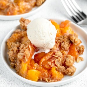 A serving of easy peach crisp recipe topped with a scoop of vanilla ice cream.