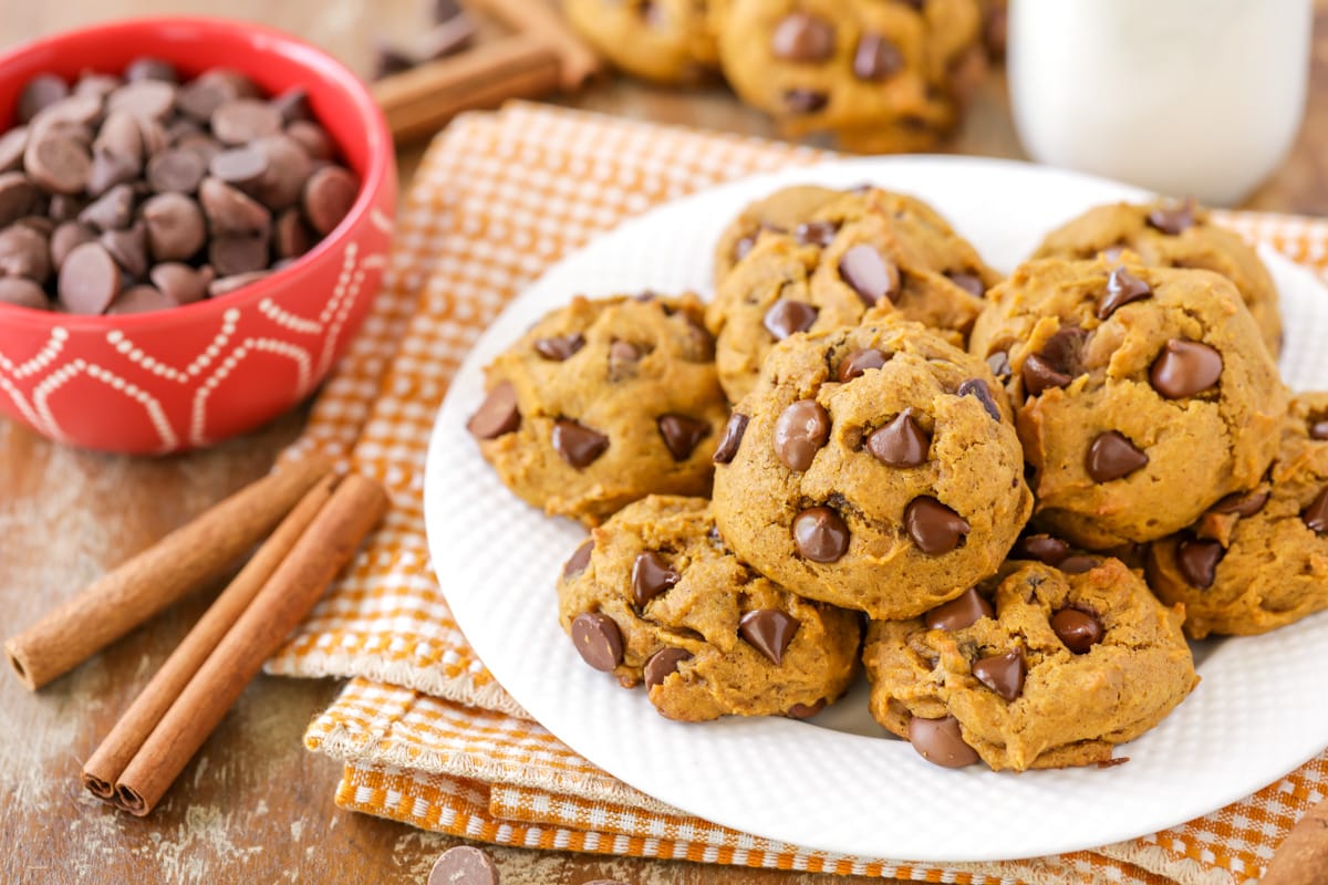 Pumpkin Chocolate Chip Cookies piled on a white plate.