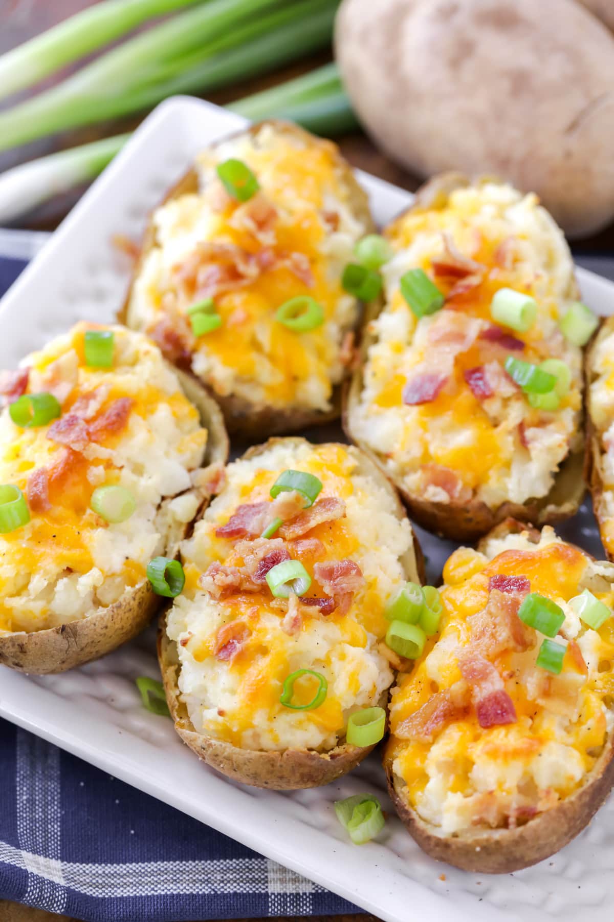 Several twice baked potato halves topped with bacon, cheese, and green onions.