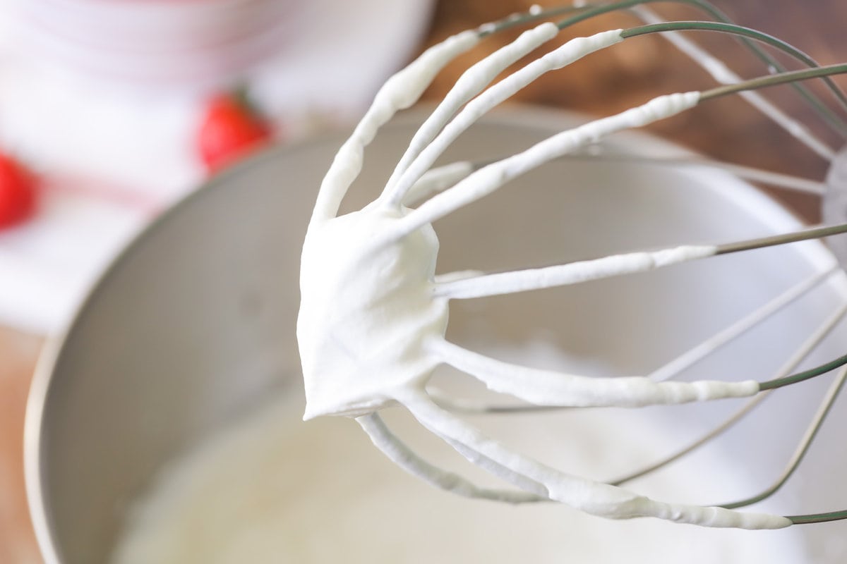 Whipped cream on a stand mixer whisk attachment.