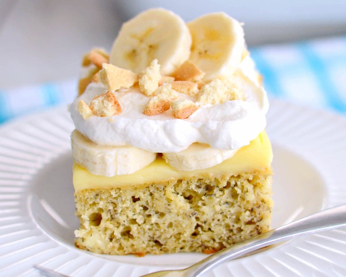 Close up of a slice of banana pudding poke cake on a white plate.