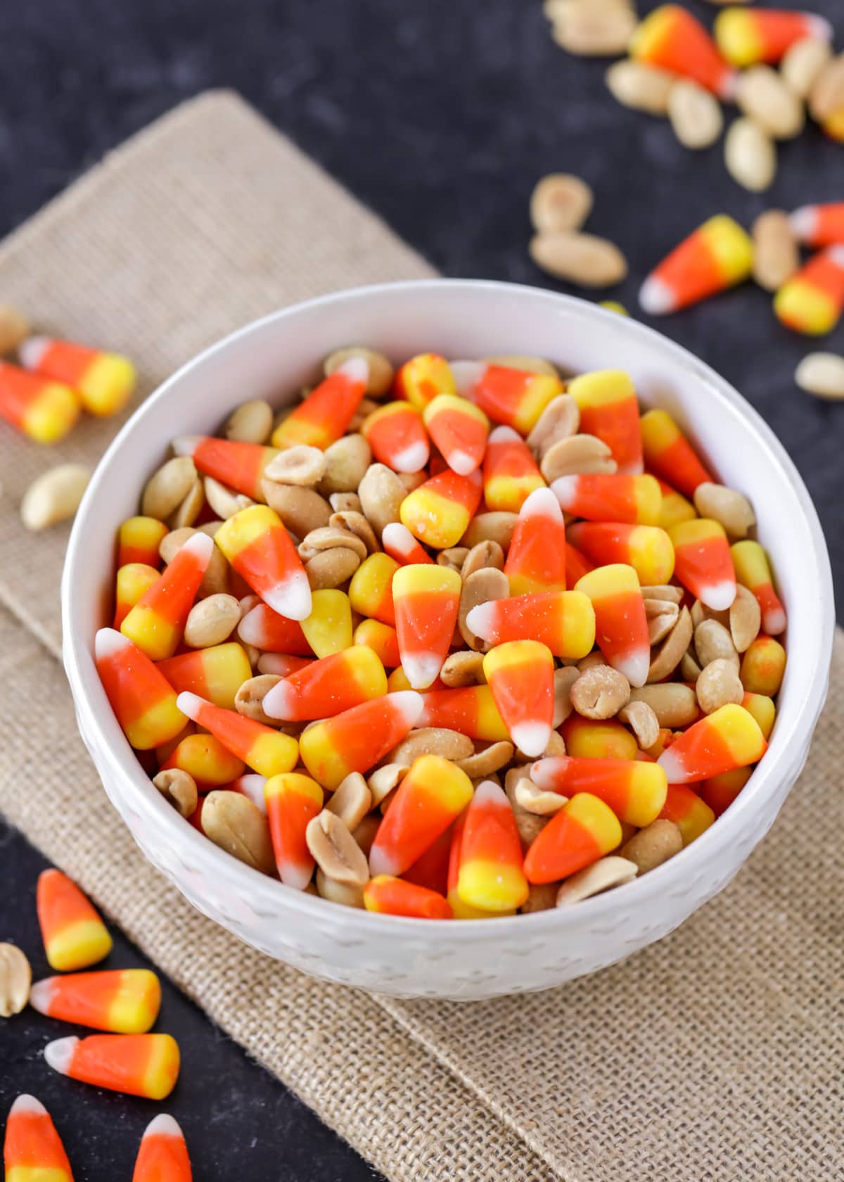Candy corn and peanuts mix in white bowl close up image.