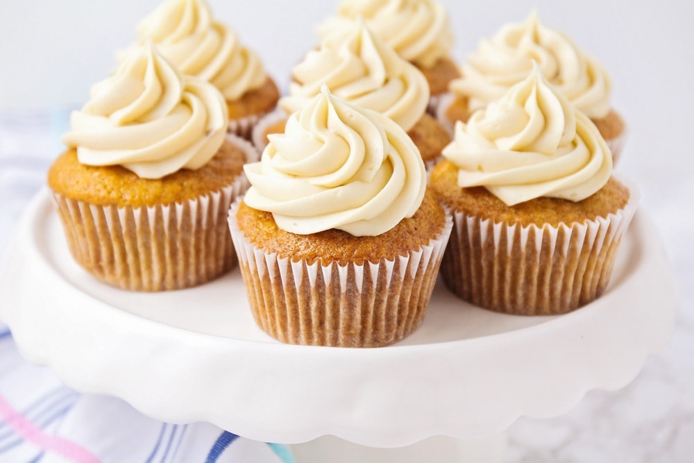 Seven cupcakes with frosting served on a white cupcake stand.