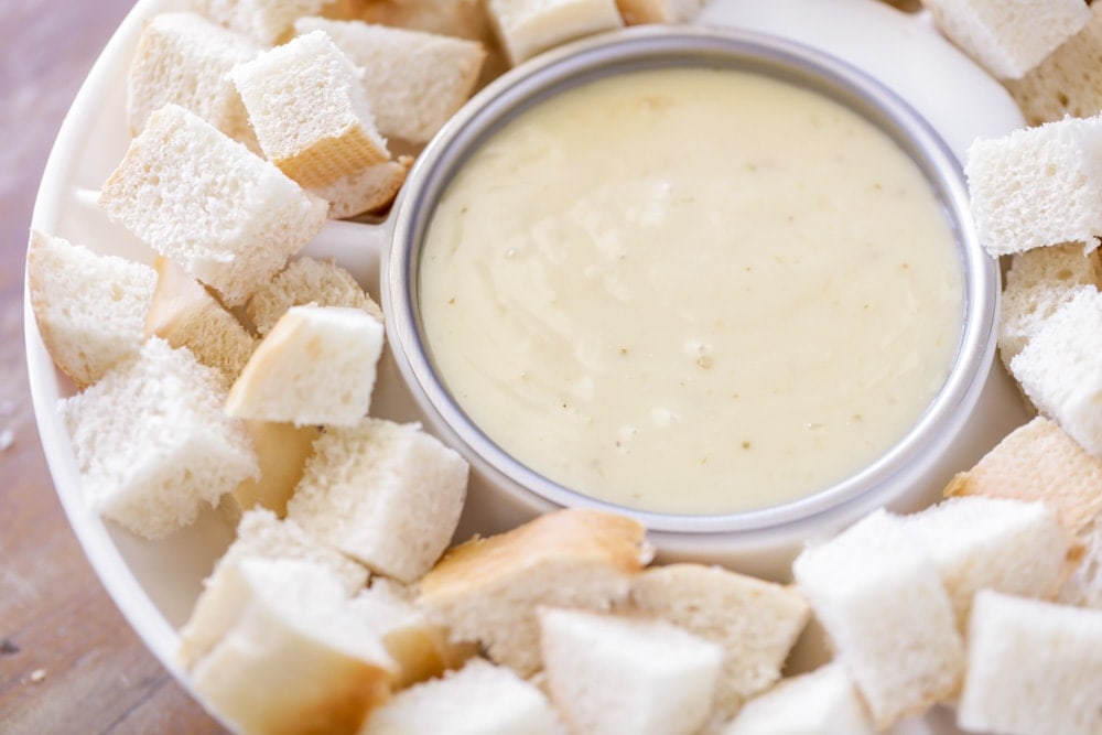 A bowl of cheese fondue surrounded by bread cubes.