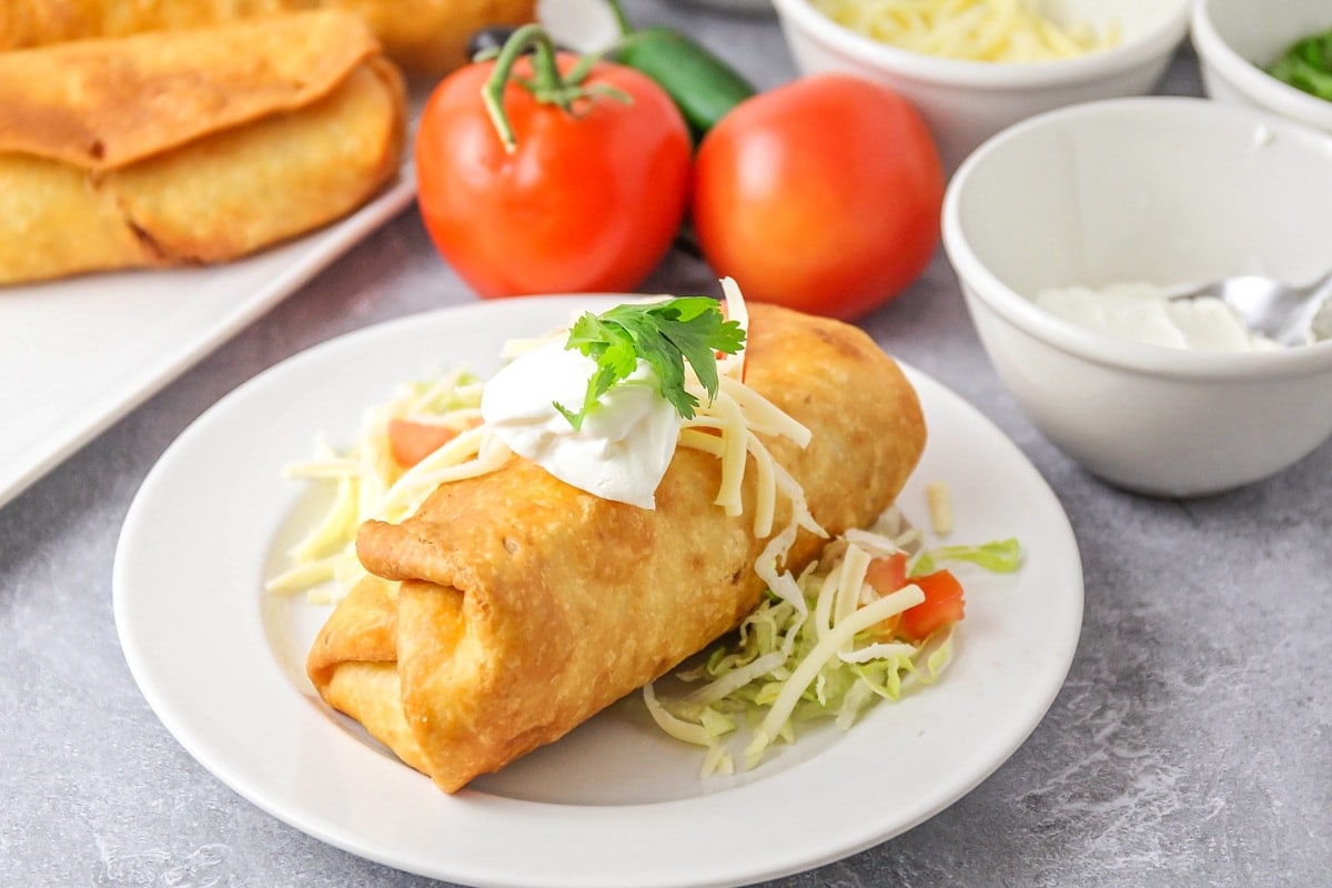 A chicken chimichanga topped with sour cream, cilantro, and pico de gallo.