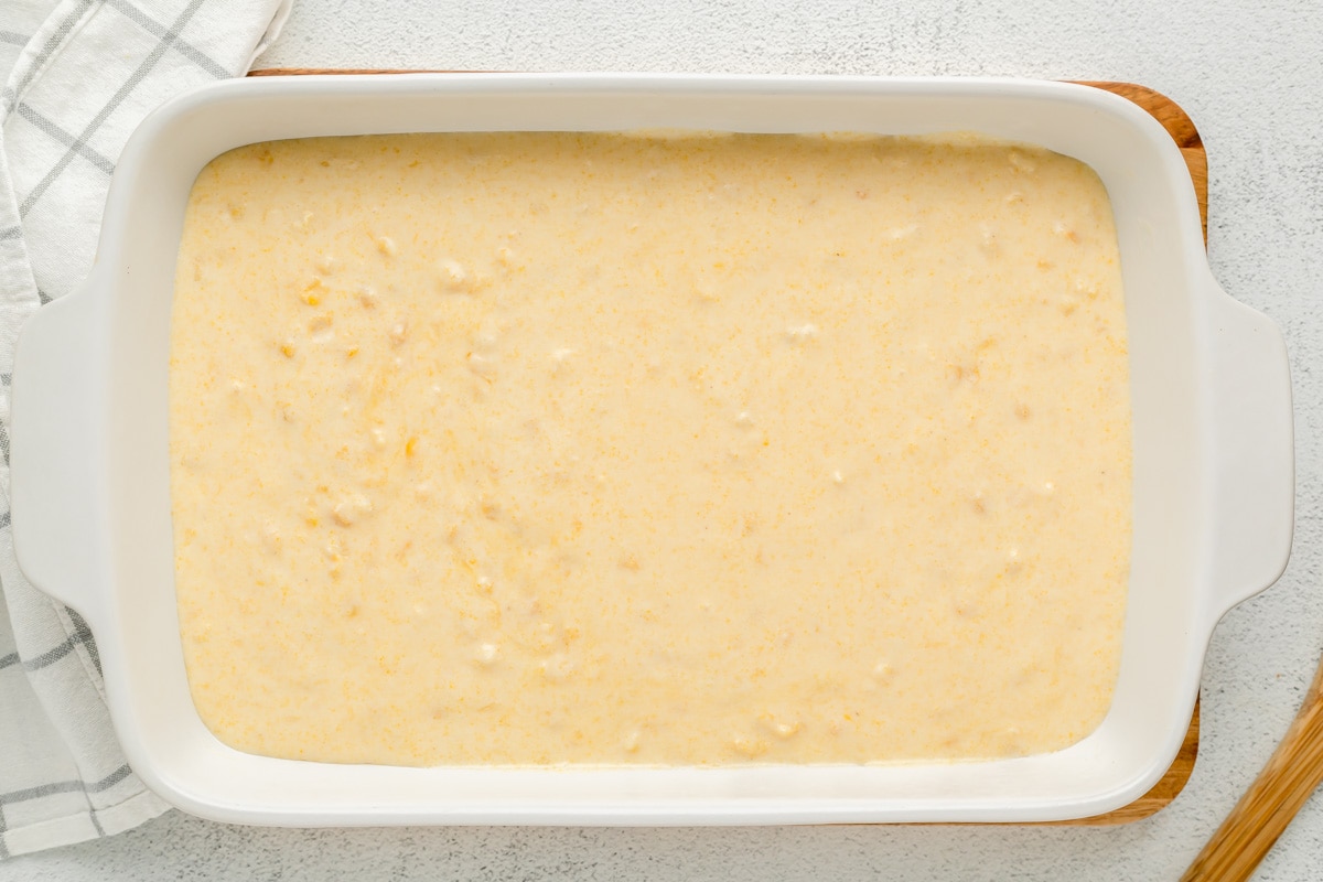 Jiffy corn pudding batter in a white casserole dish ready for baking.