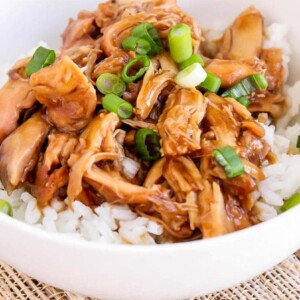Crock pot teriyaki chicken served over white rice and topped with green onions.