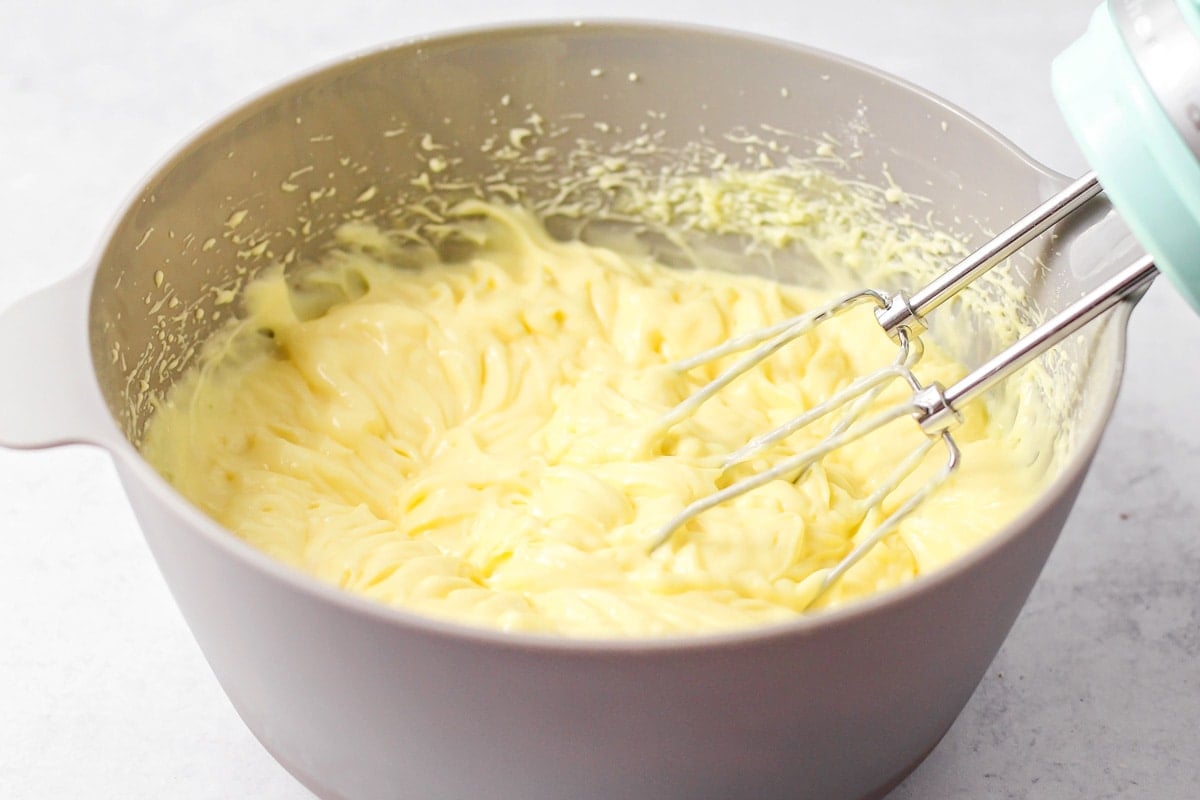 Mixing the creamy filling for cream puff cake in a mixing bowl.