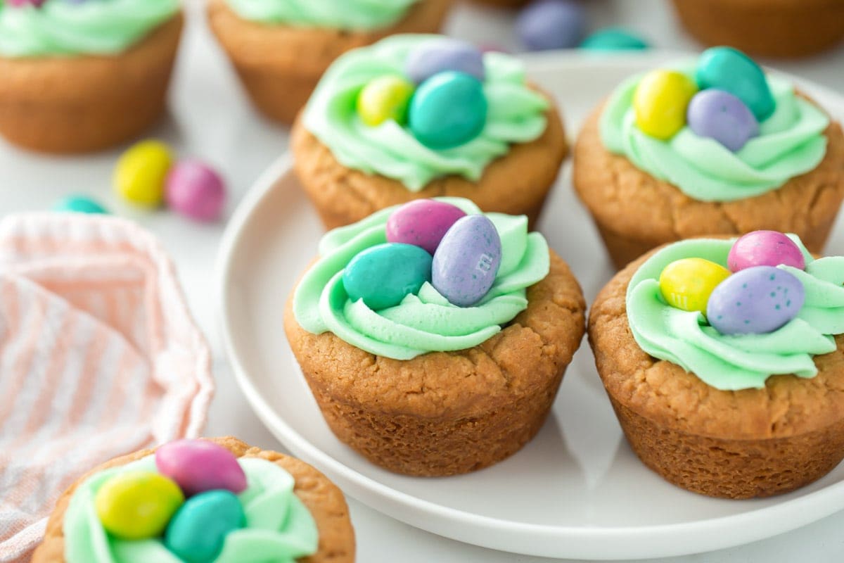 Cupcakes topped with frosting and Easter candies served on a white platter.
