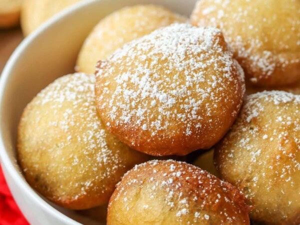 A bowl of fried oreos topped with powdered sugar.