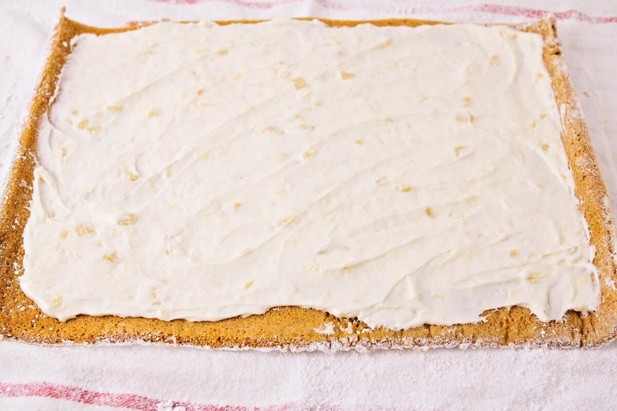 This delicious spiced Libby's pumpkin roll filled with tangy pineapple cream cheese frosting is a classic fall favorite! Spreading cream cheese filling on a baked cake.