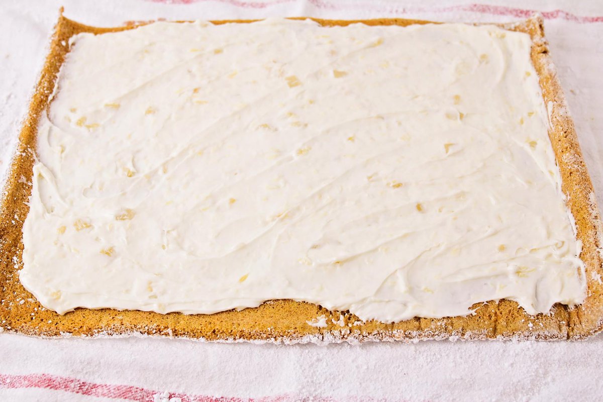 Spreading cream cheese filling on a baked cake.