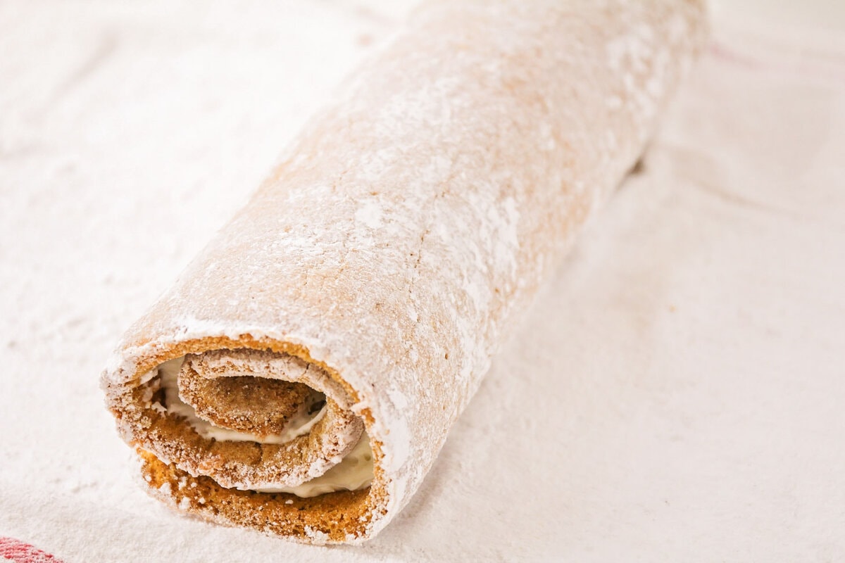 A filled pumpkin roll on a tea towel.