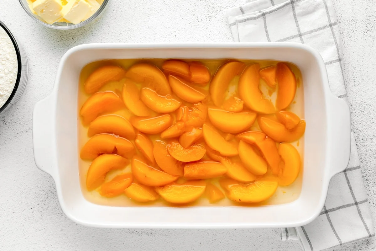 Peaches in baking dish for peach dump cake recipe.