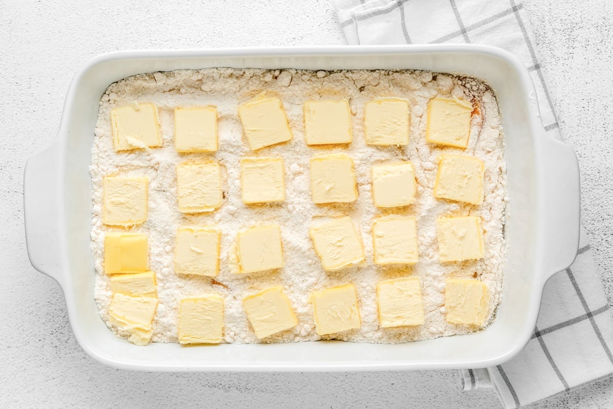 Butter slices over cake mix and peaches for easy peach dump cake recipe.