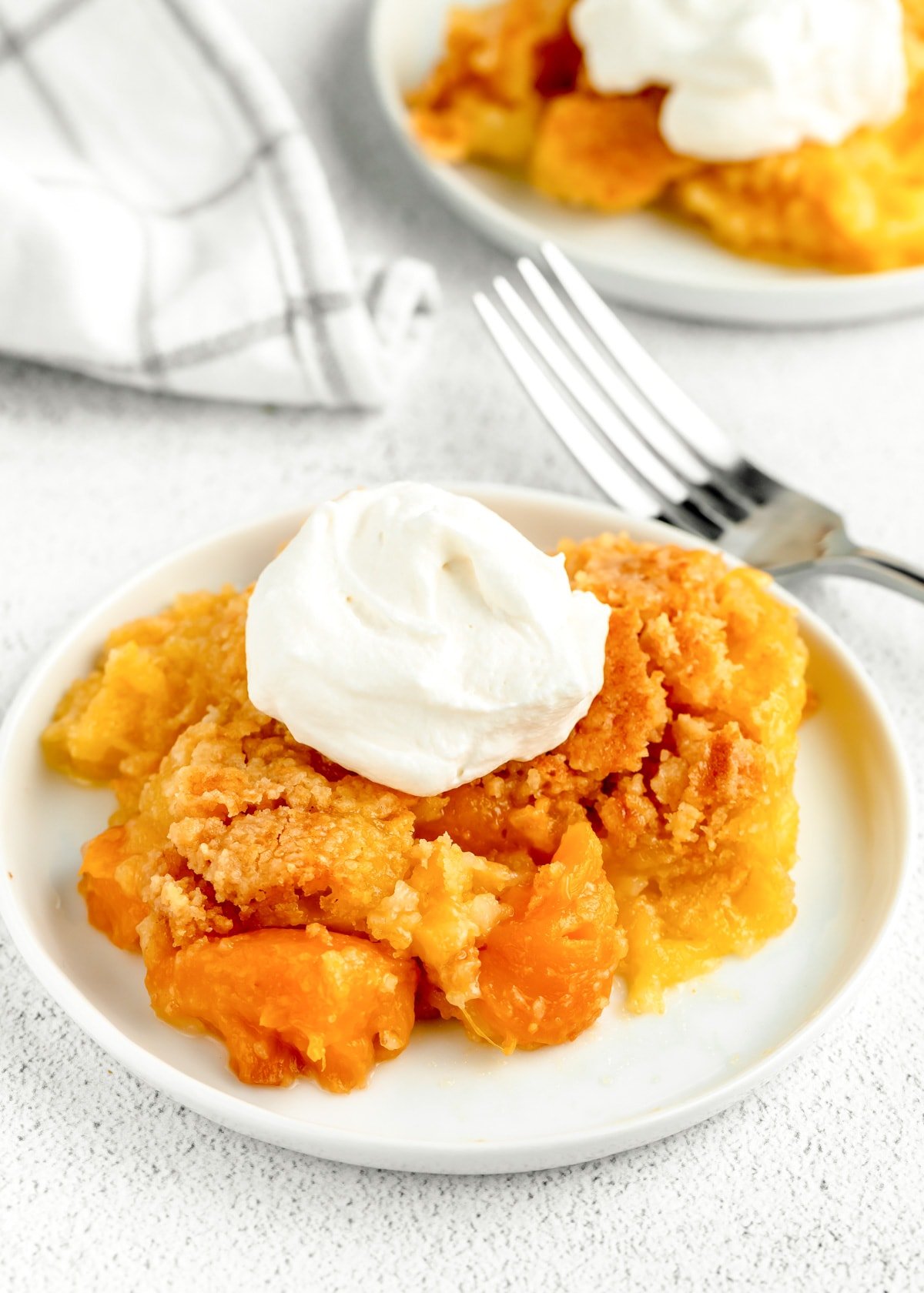Easy Peach dump cake with whipped cream close up image.