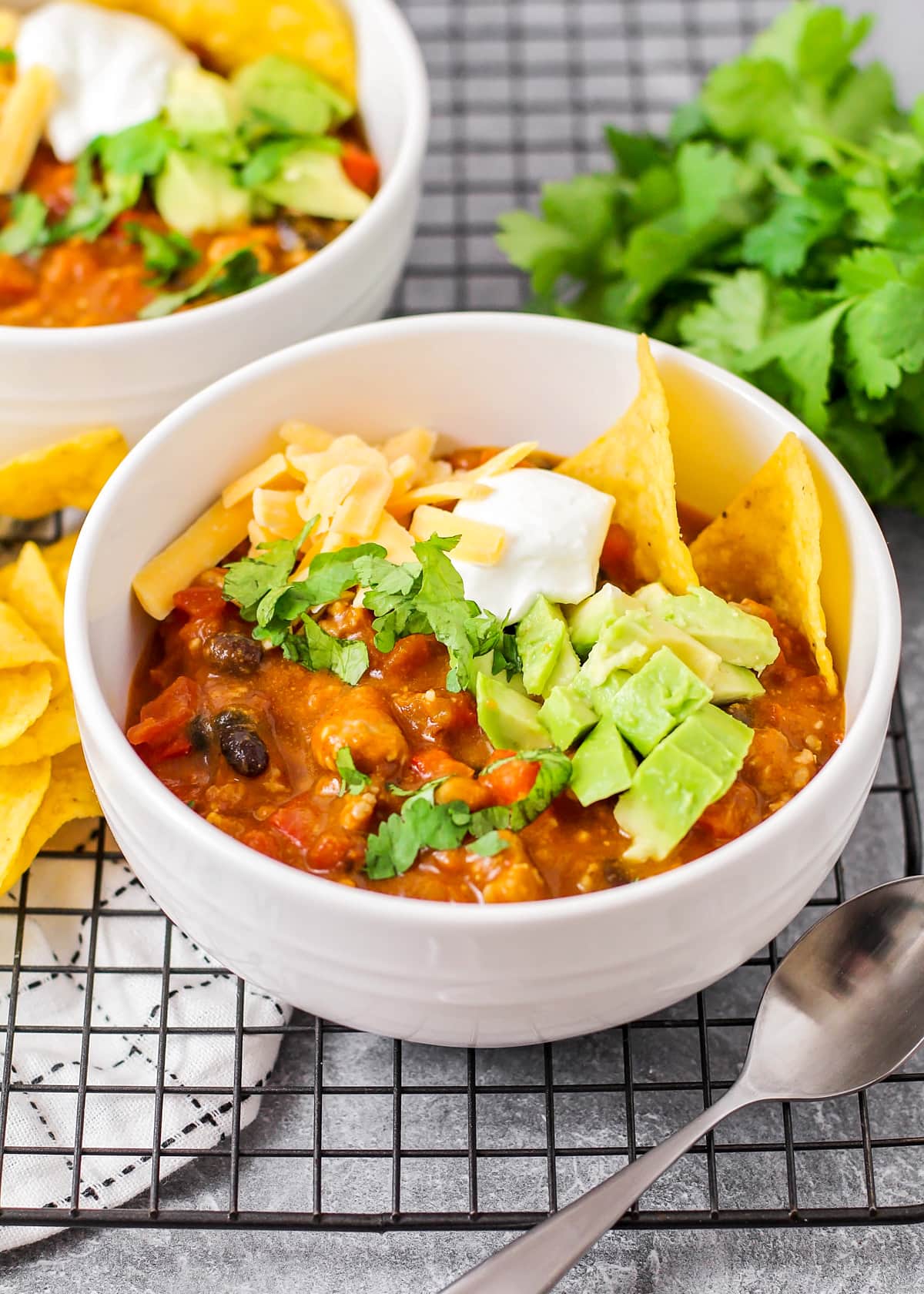 Recipe for hearty pumpkin chili with garnishes served in a white bowl.