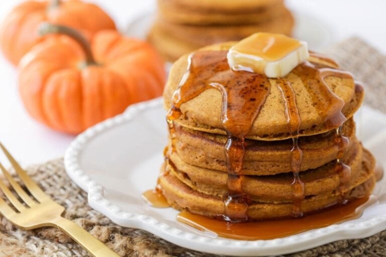 Pumpkin pancakes stacked and drizzled with syrup.