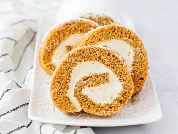 Homemade pumpkin roll sliced and served on a plate.