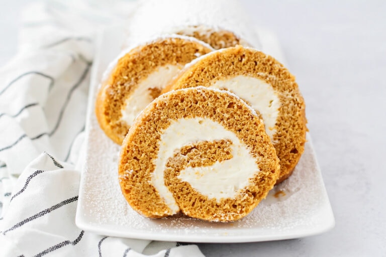 Homemade pumpkin roll sliced and served on a plate.