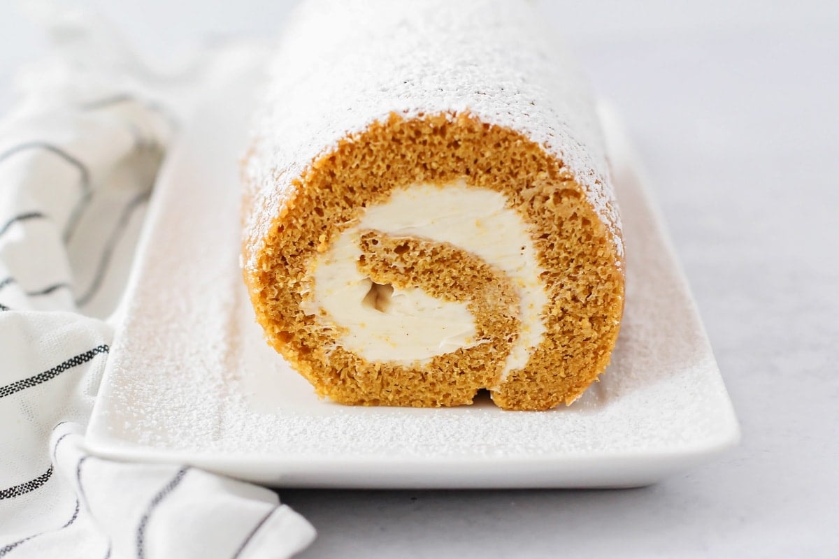 The side view of a rolled pumpkin roll dusted with powdered sugar.