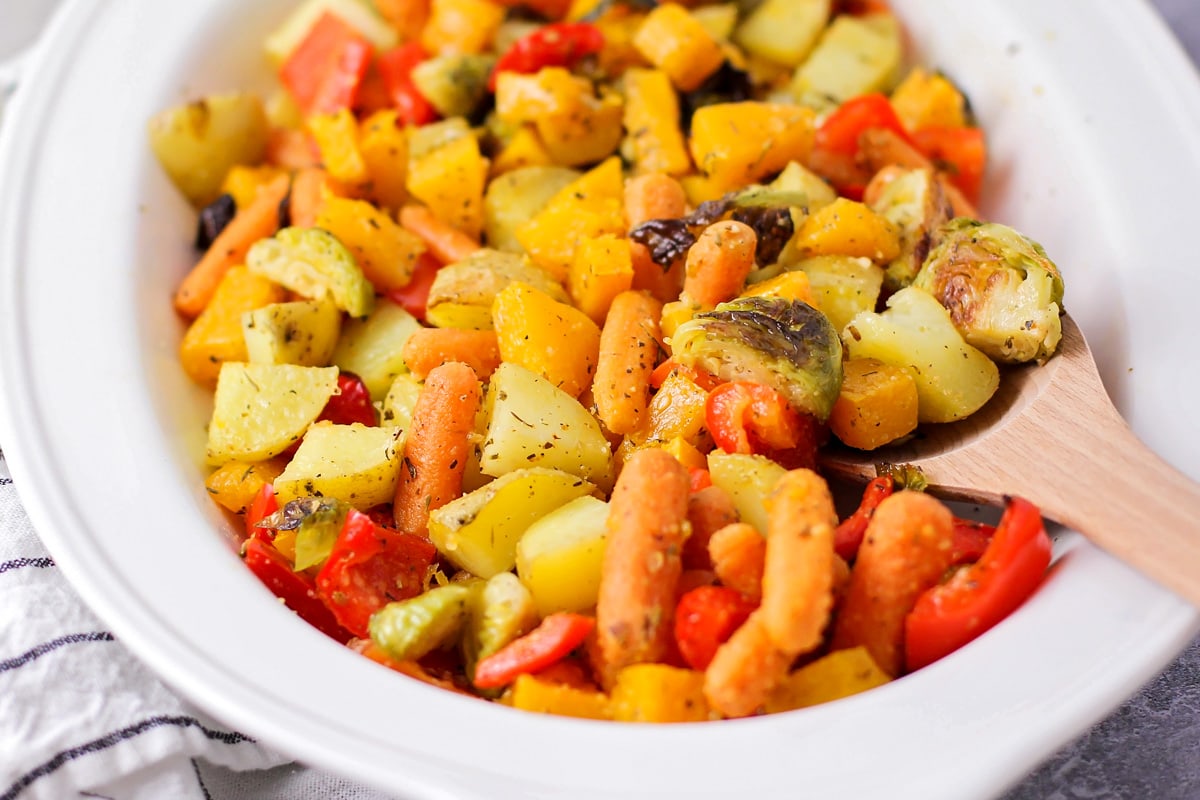 Oven roasted vegetables with seasonings in white bowl.