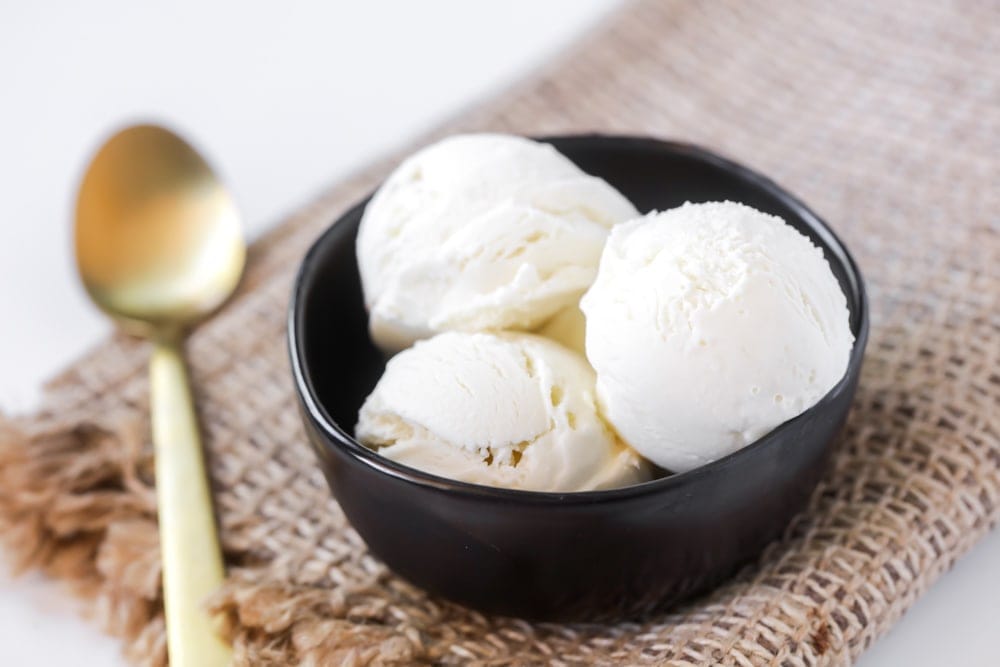 Vanilla ice cream scooped in a black bowl.