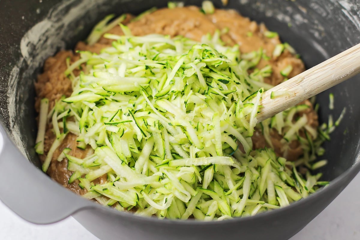 Zucchini bread batter in bowl with grated zucchini on top.